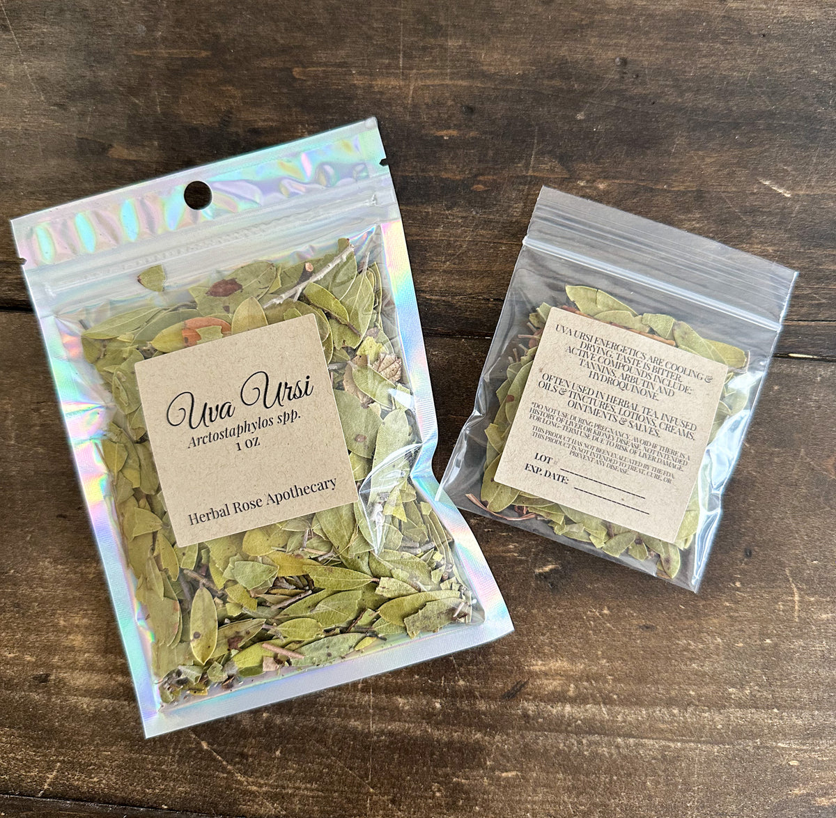 two packages of dried uva ursi leaves in clear resealable bags from herbal rose apothecary on a wooden surface