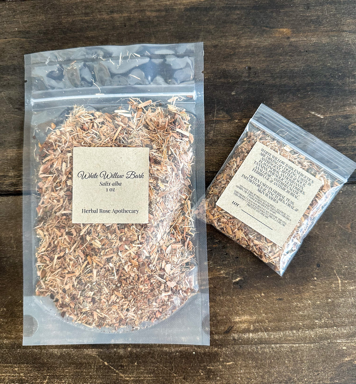 two packages of dried white willow bark in clear resealable bags from herbal rose apothecary on a wooden surface