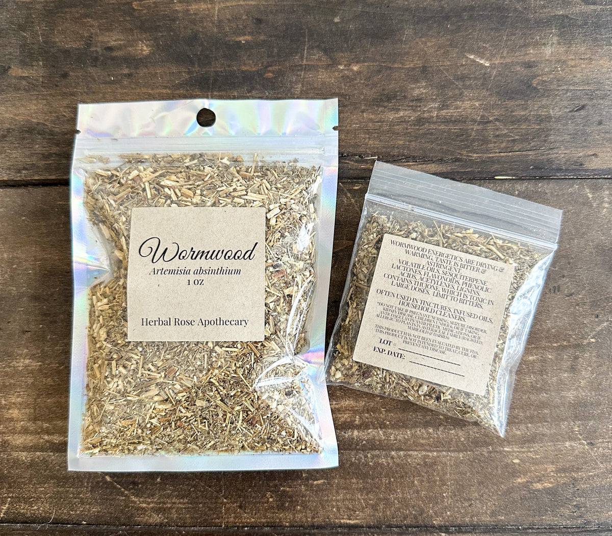 two packages of dried wormwood leaves in clear resealable bags from herbal rose apothecary on a wooden surface