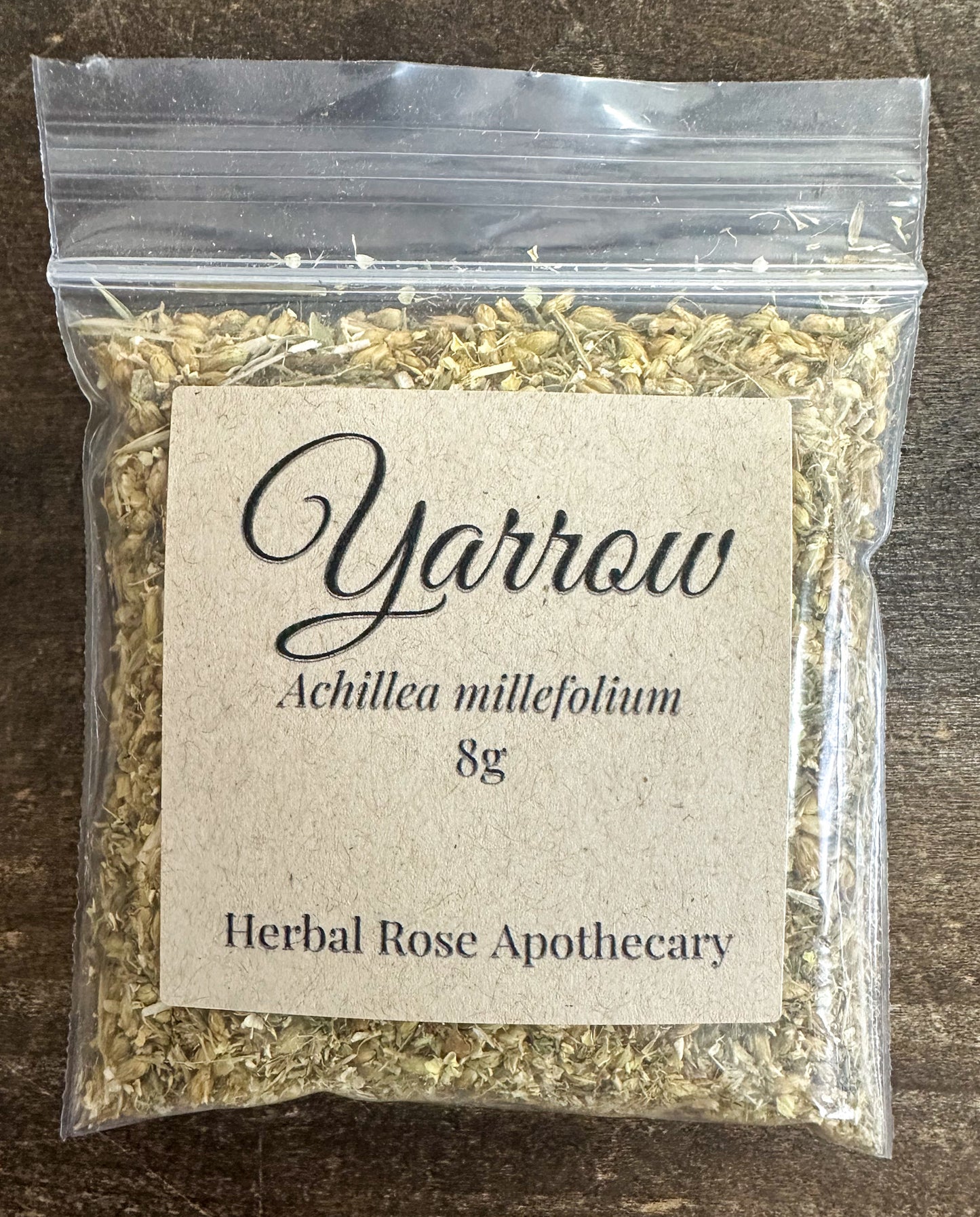 dried yarrow in 8g clear resealable bag on wooden surface