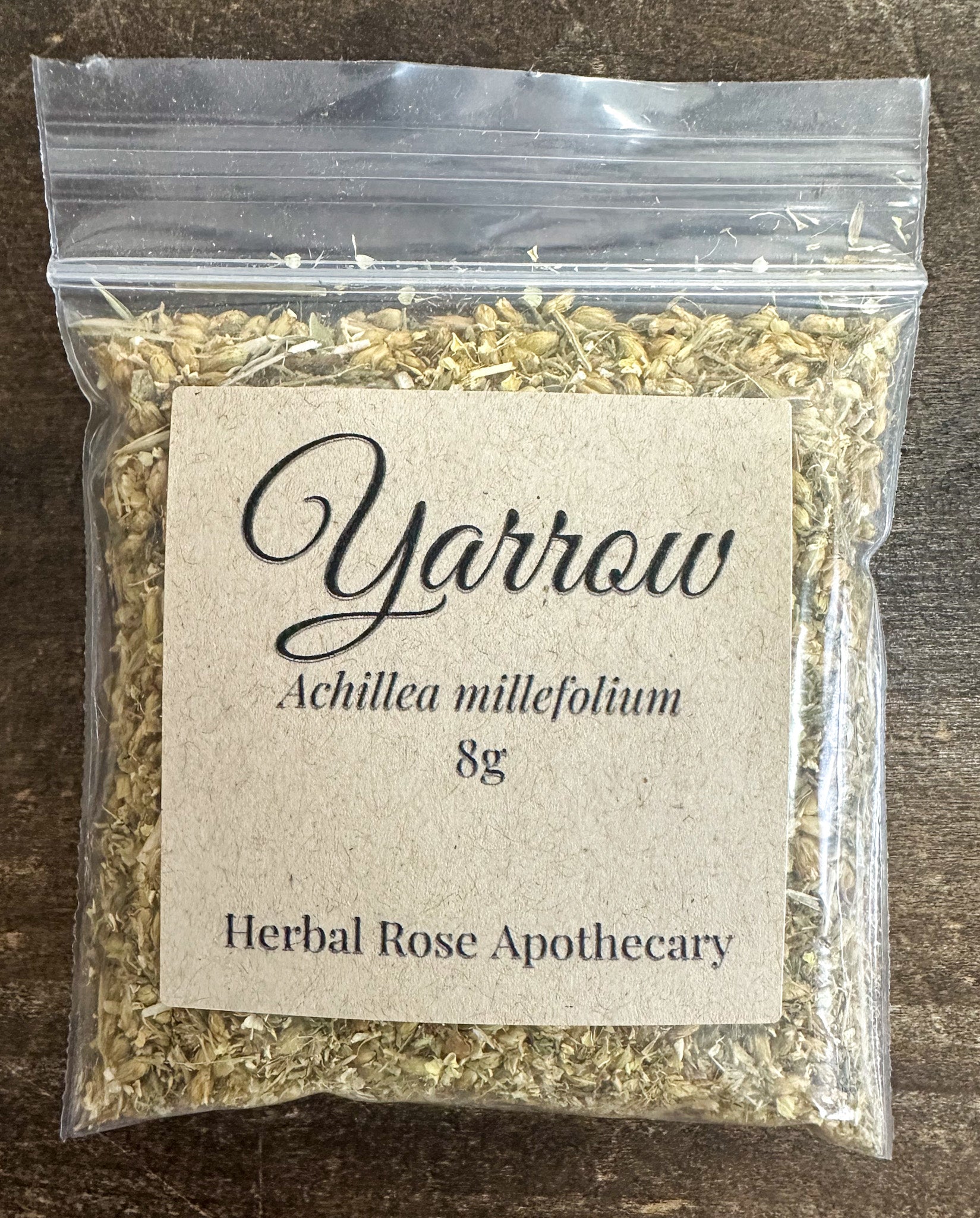 dried yarrow in 8g clear resealable bag on wooden surface