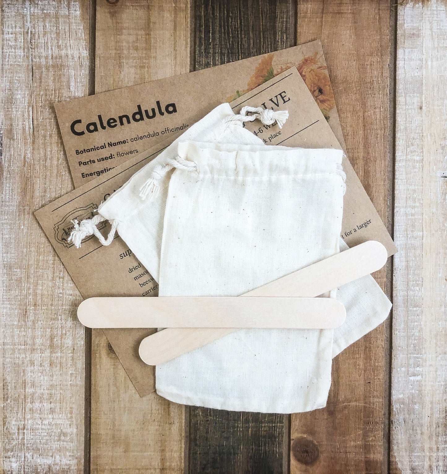monograph card, instructions card laying on a wooden table covered partly with 2 muslin bags and 2 tongue depressors