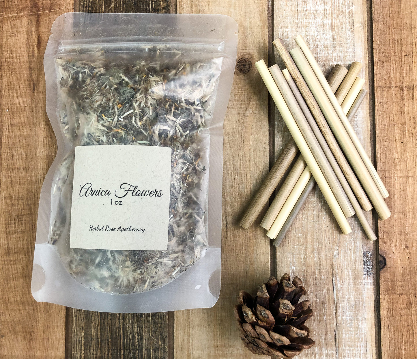 dried arnica flowers with wood planks as a background and sticks in a pile off the side and a pine cone