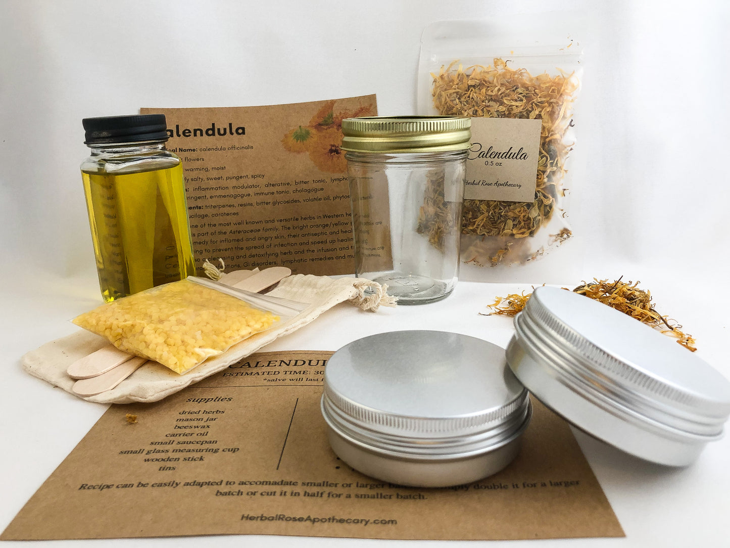 calendula salve kit with white background. Kit includes 2 metal tins, dried calendula, muslin bag, beeswax, 2 tongue depressors, carrier oil, mason jar, monograph, and directions