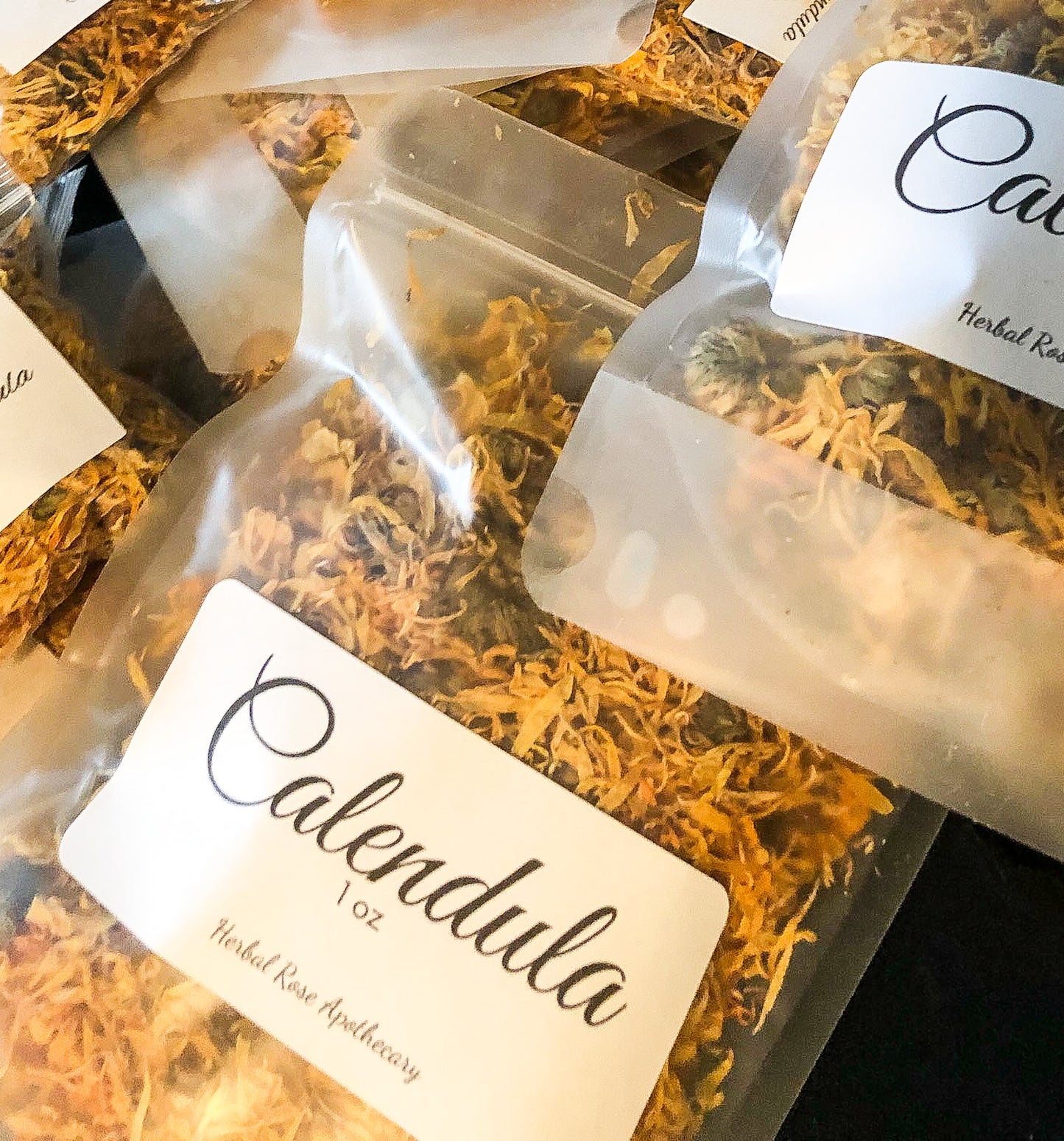 several clear bags filled with dried calendula flowers with image focused on a 1oz bag 