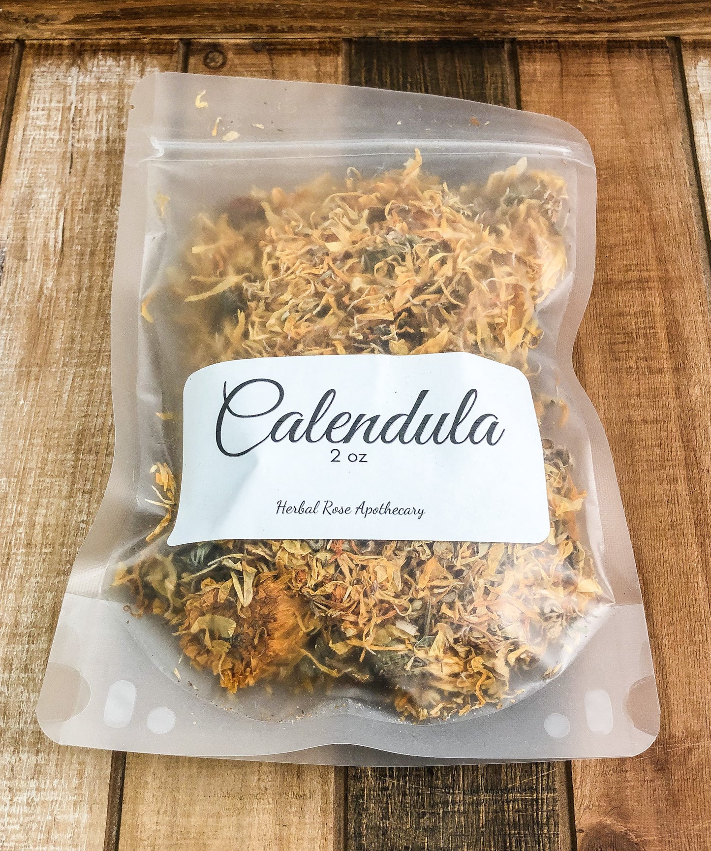 2oz dried calendula flowers in a clear plastic bag with a wooden background