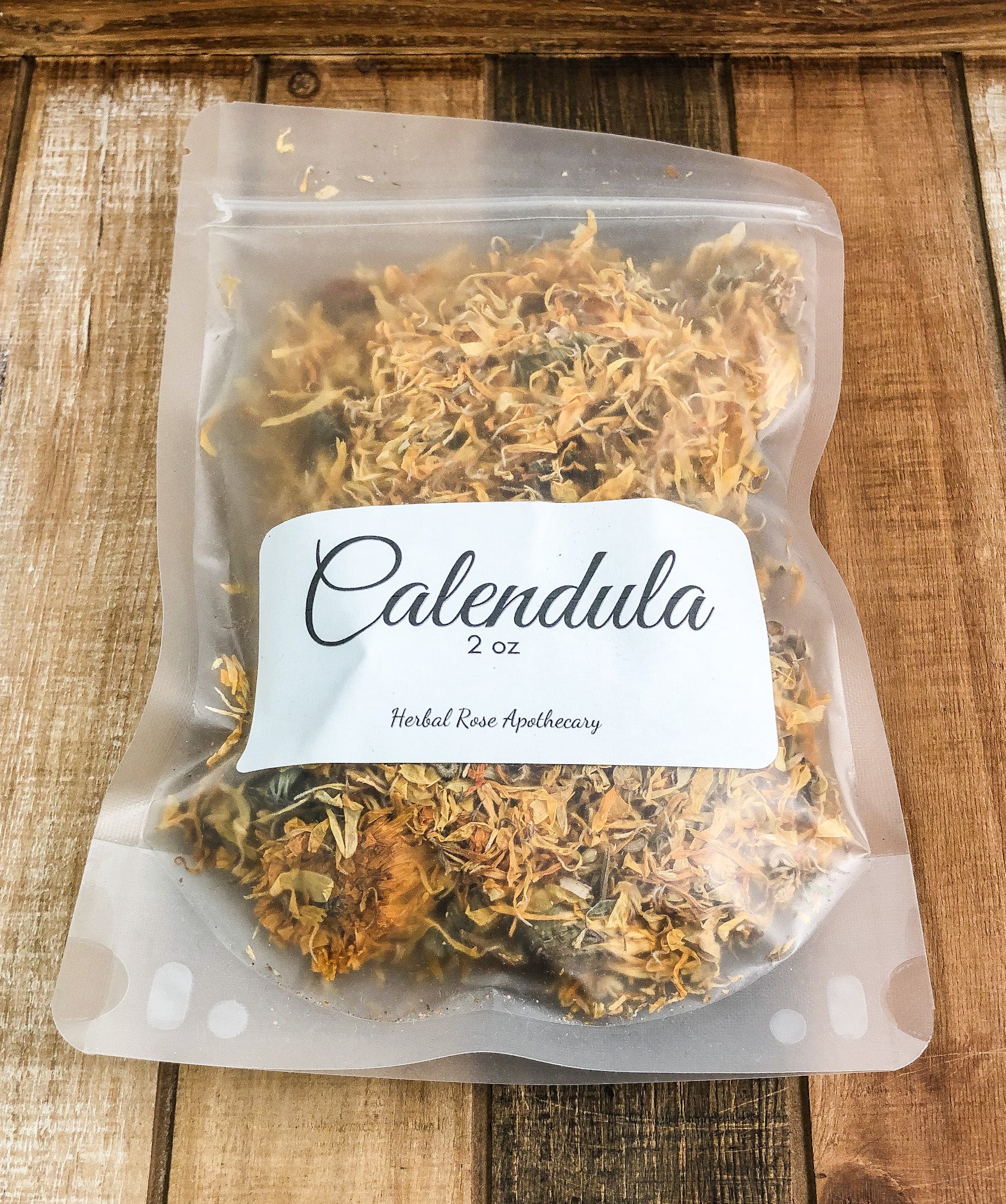 2oz dried calendula flowers in a clear plastic bag with a wooden background