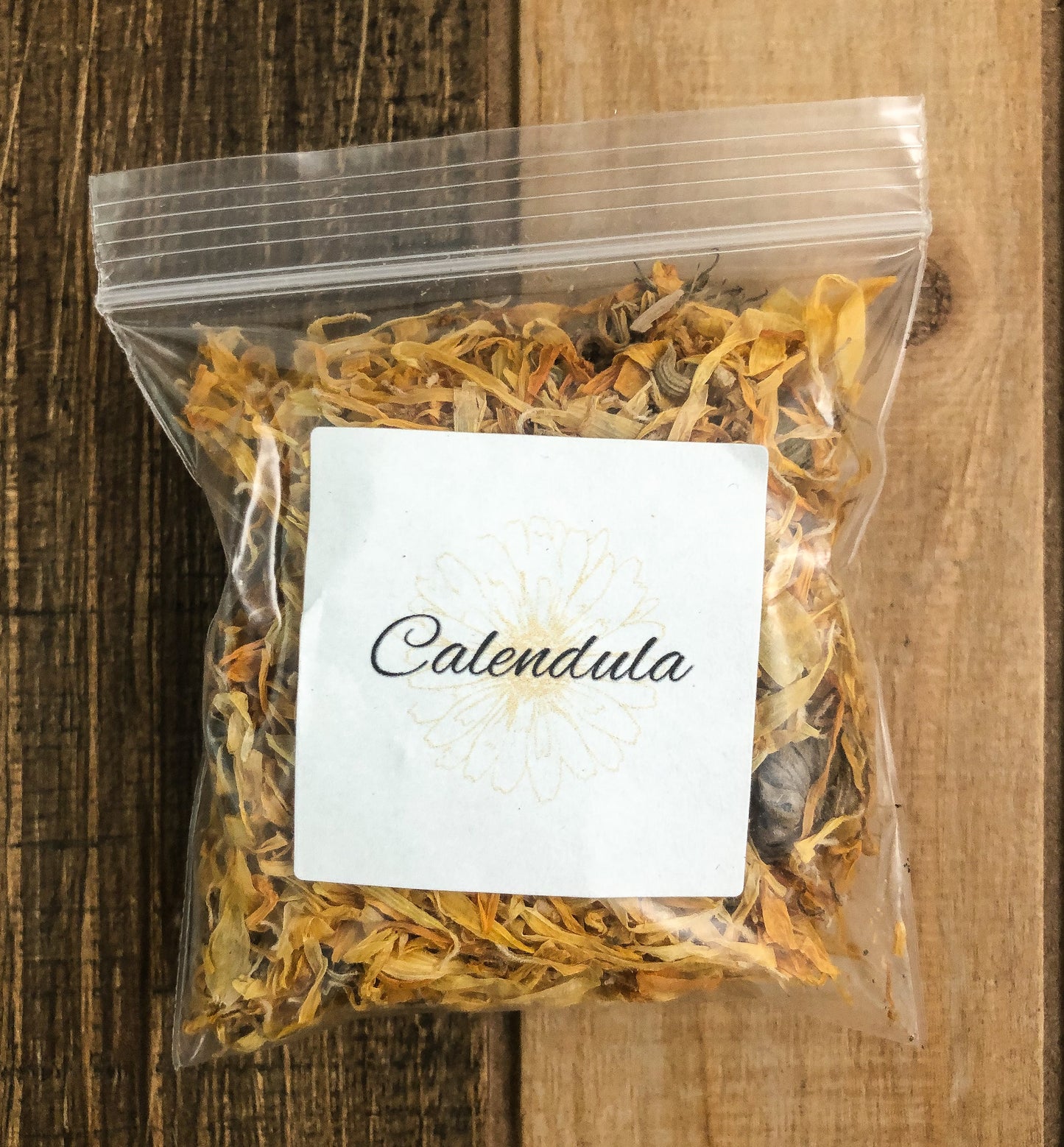 8g bag of dried calendula in a clear plastic bag with a wooden background
