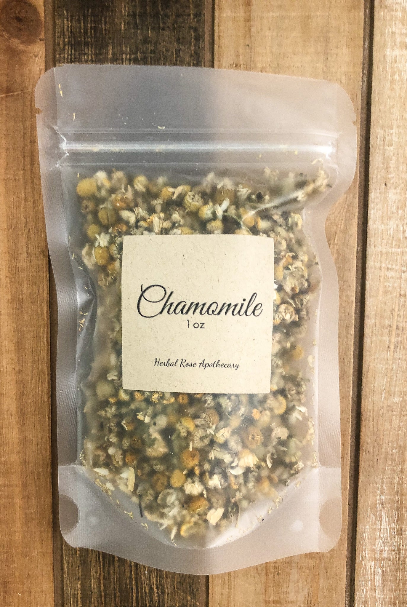 1oz dried chamomile in a clear plastic bag with a wooden background