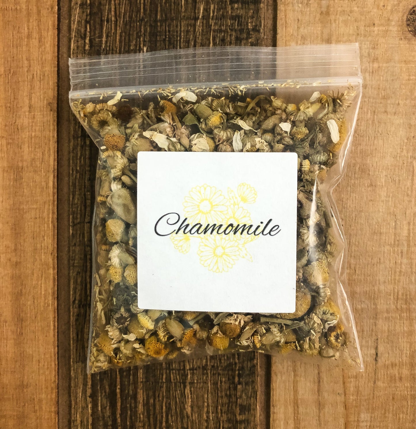 8g bag of dried chamomile in a clear plastic bag with a wooden background