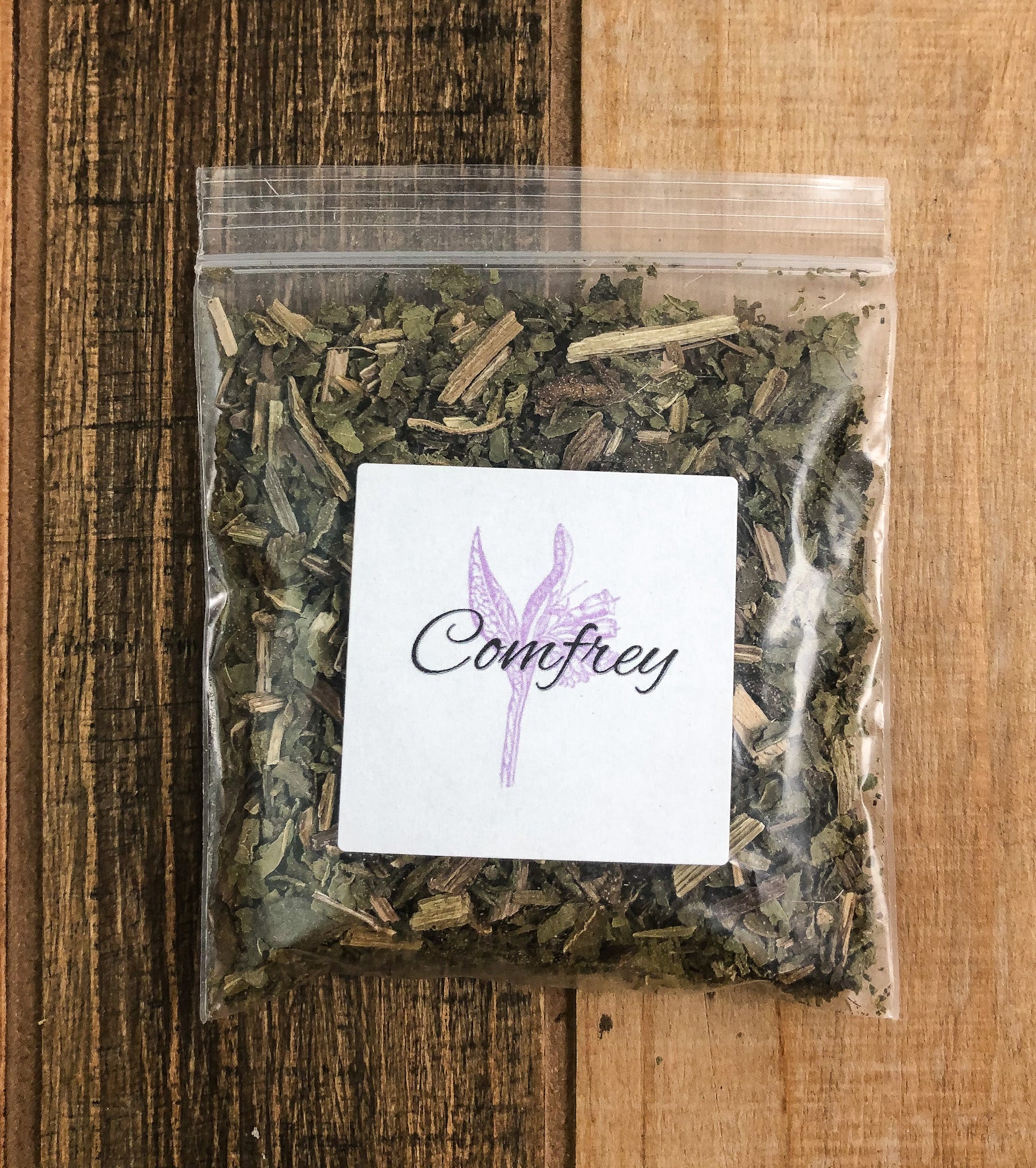 8g bag of dried comfrey in a clear plastic bag with a wooden background