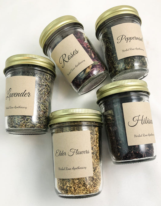 dried herbs in clear glass jars with white white background