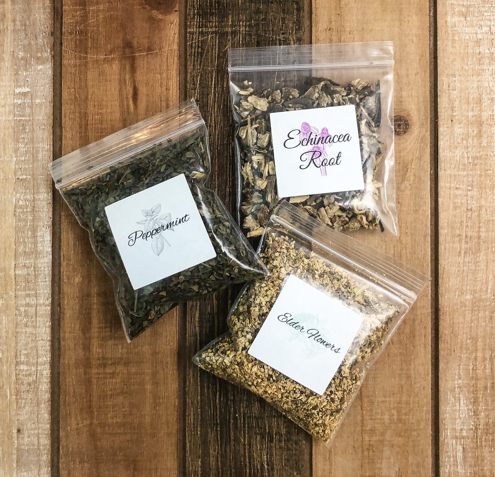 8g clear plastic bags of dried echinacea root, peppermint, and elder flowers on a wooden background