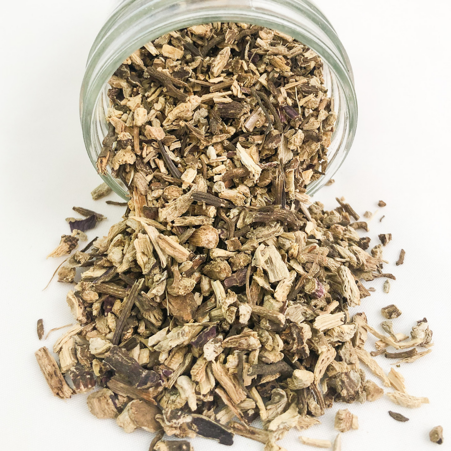 upclose image of dried echinacea spilling out of a clear glass jar with a white background