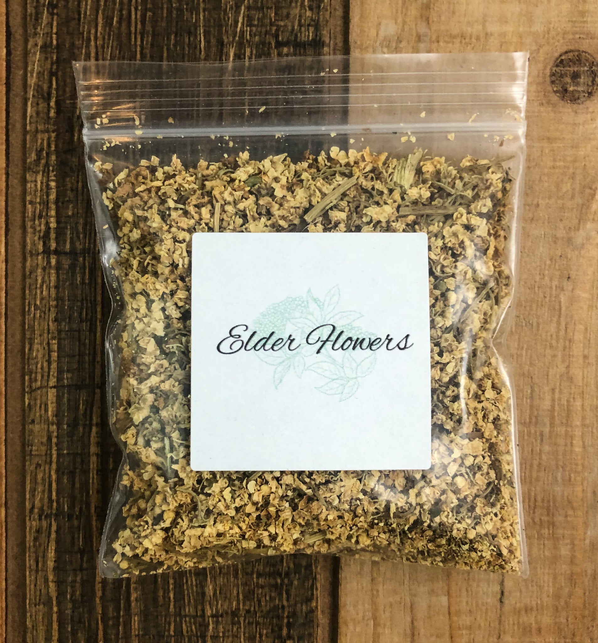 8g bag of dried elder flowers in a clear plastic bag with a wooden background