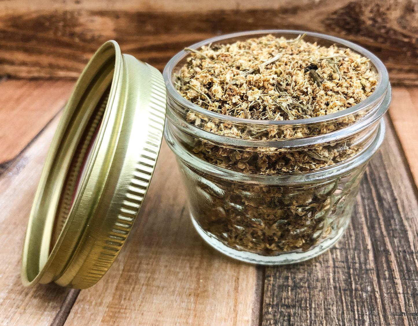 dried elder flowers in a clear mini mason jar with a wooden background