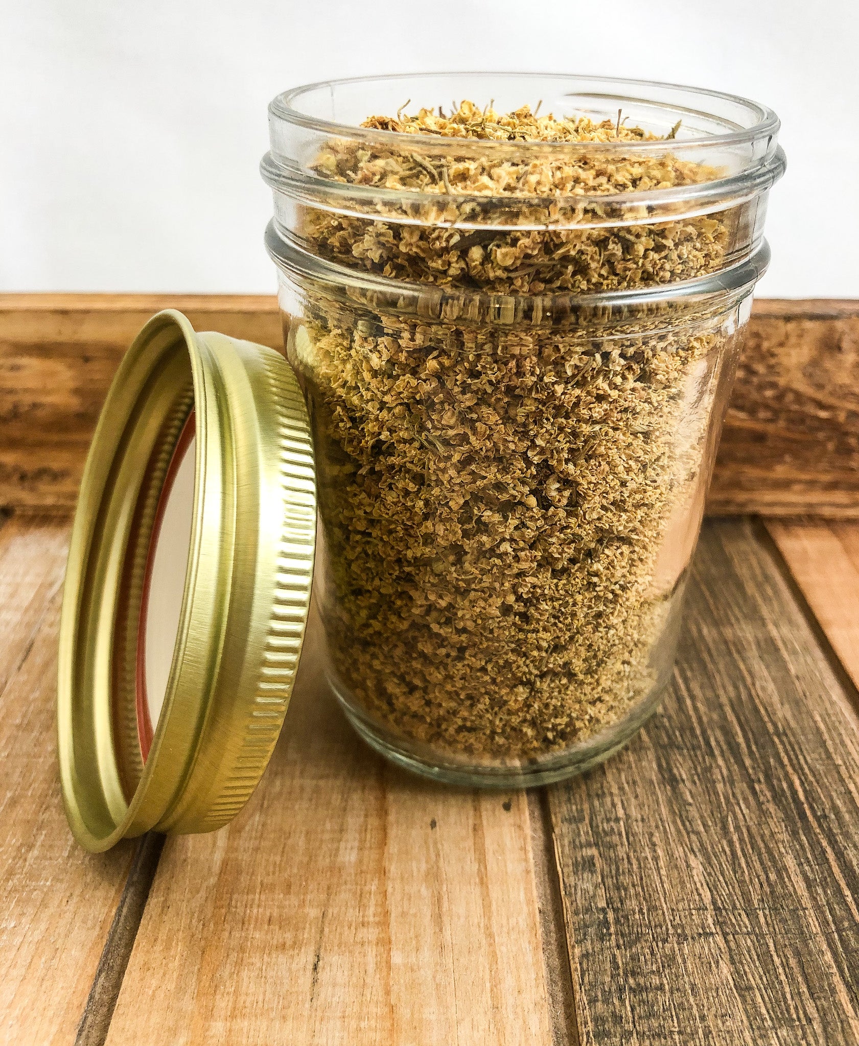 dried elder flowers in a clear mason jar with a wooden background