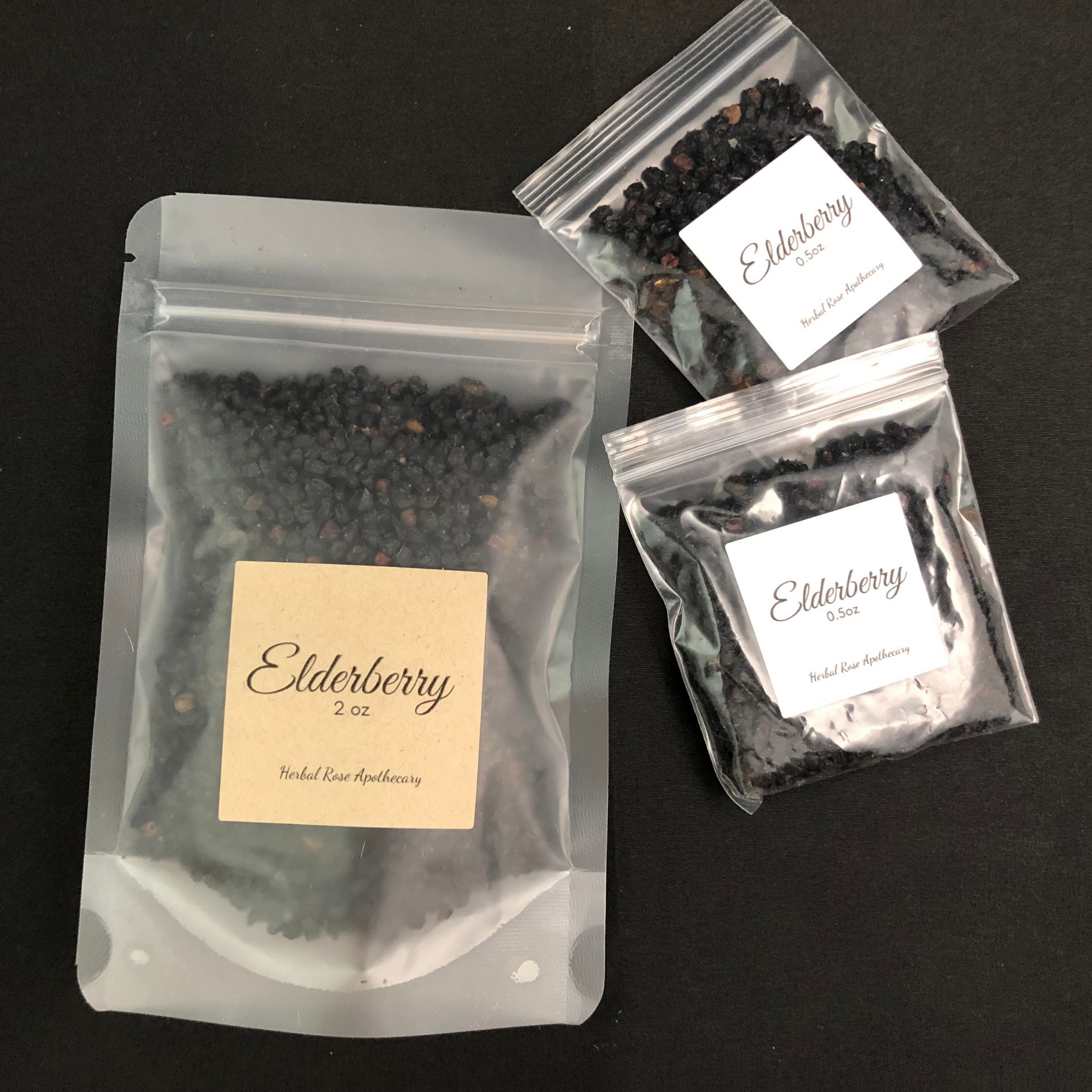 elderberry in clear 2oz bag, next to 2 elderberry bags in clear 0.5oz bag with a black background