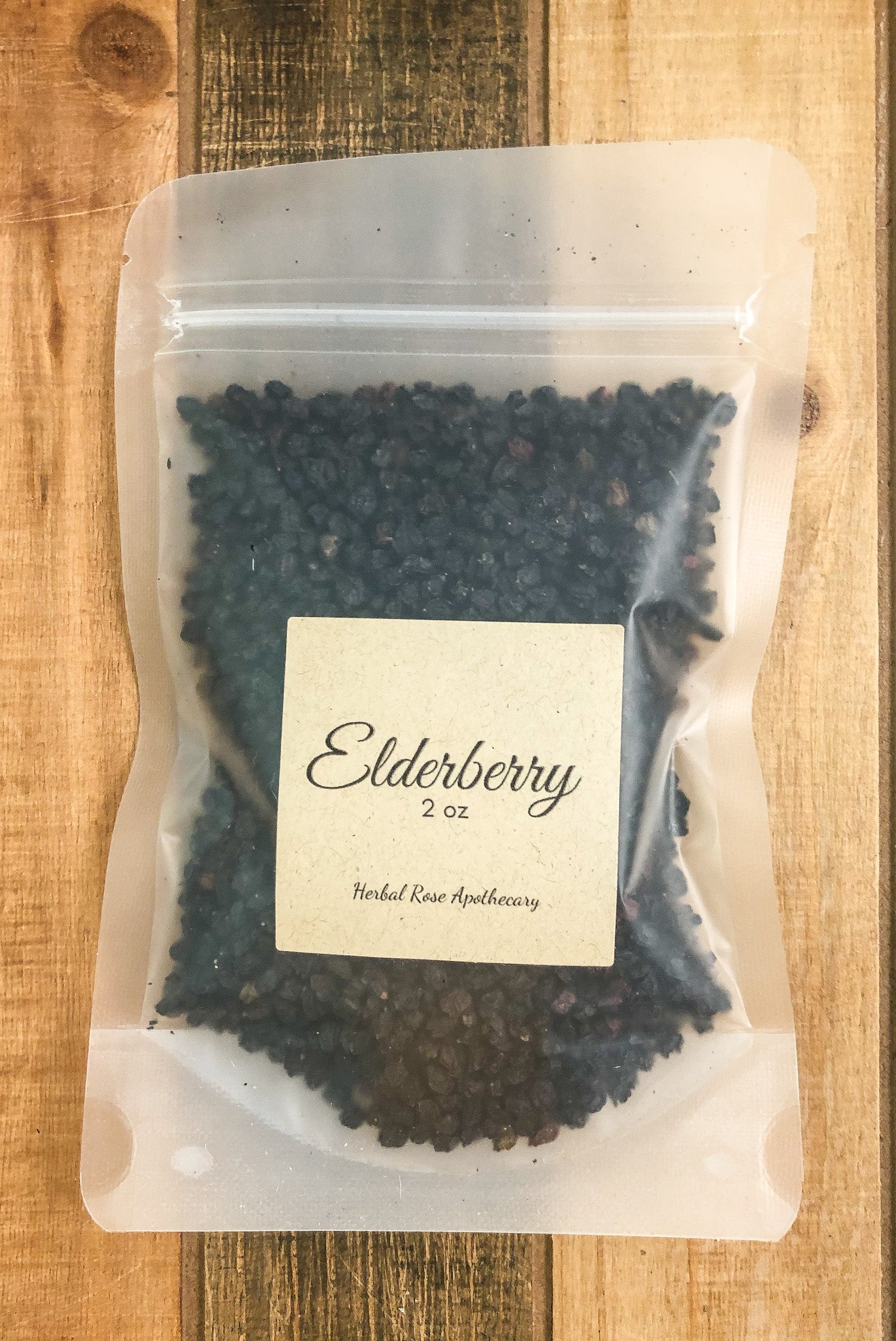 2oz bag of dried elderberries in a clear plastic bag with a wooden background