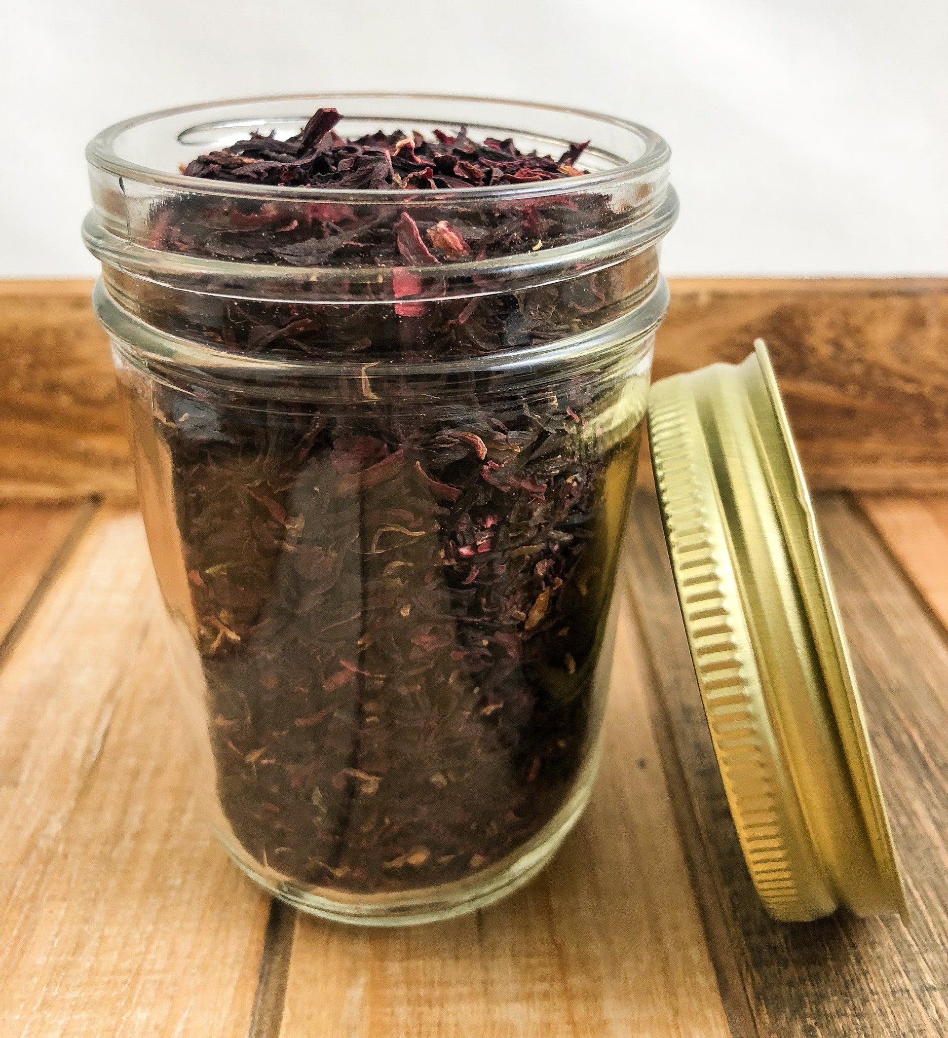 dried hibiscus in a clear mason jar with a wooden background