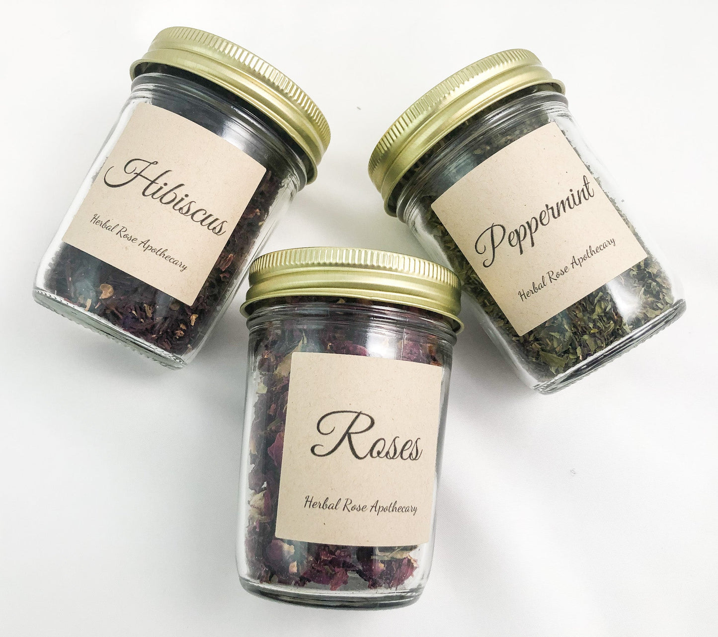 Ariel view of 3 clear glass jars filled with dried herbs laying on white background