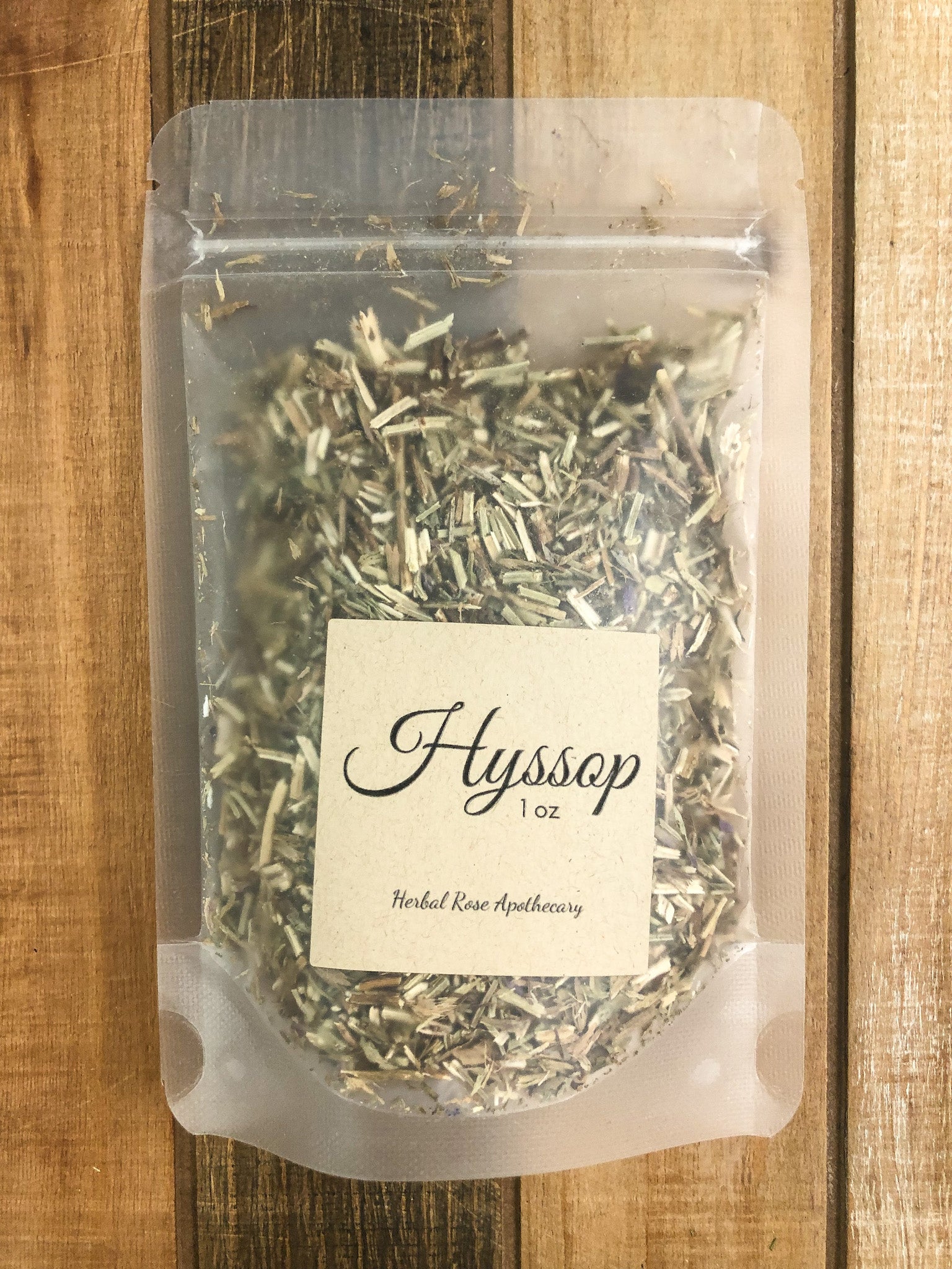 1oz bag of dried hyssop in a clear plastic bag with a wooden background