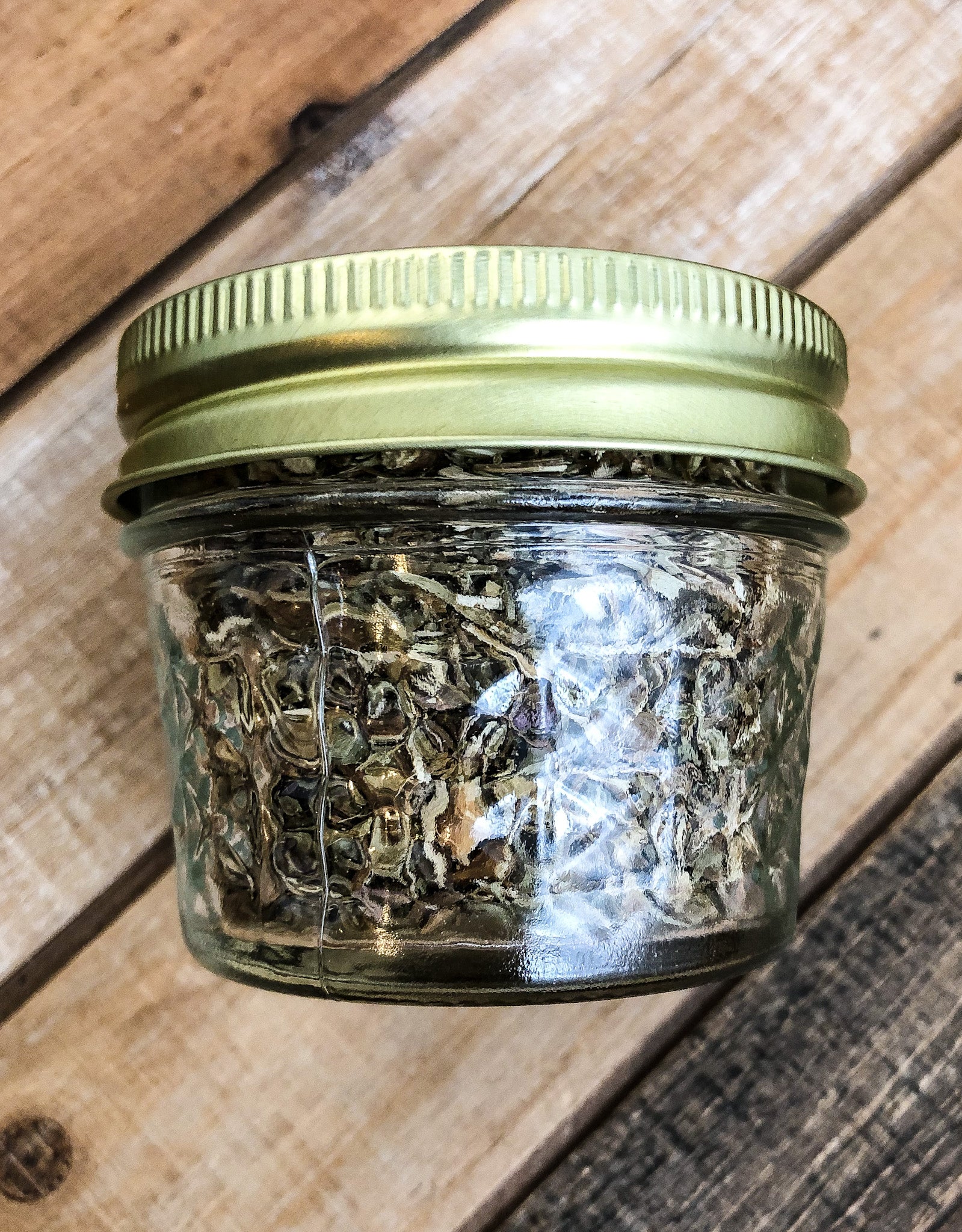 dried hyssop in a clear mini mason jar with a wooden background