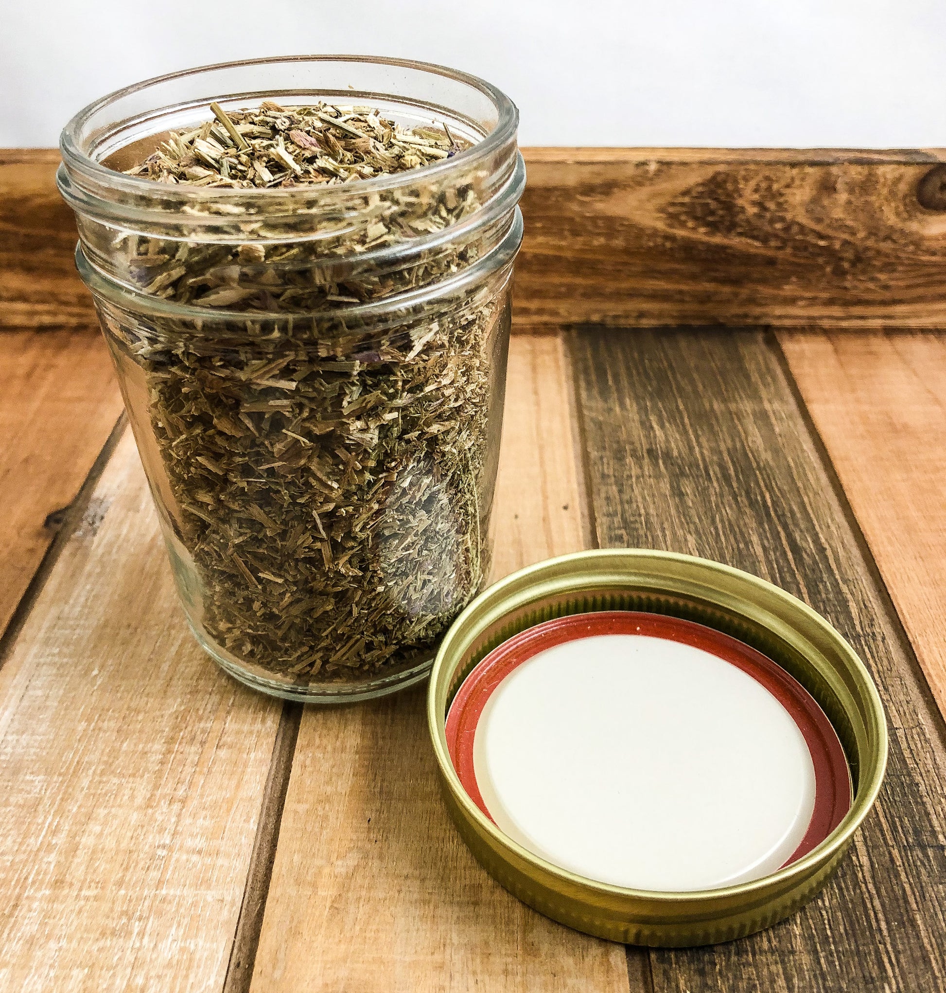dried hyssop in a clear mason jar with a wooden background