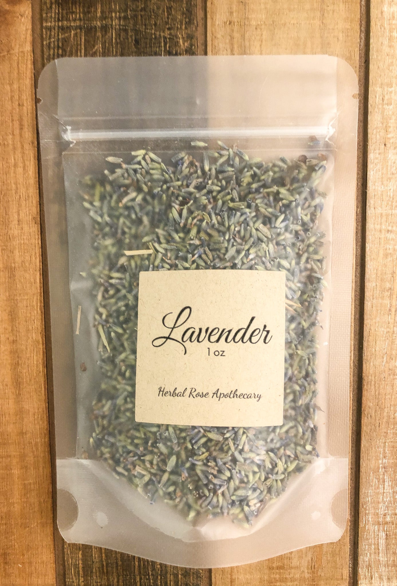 1oz bag of dried lavender in a clear plastic bag with a wooden background