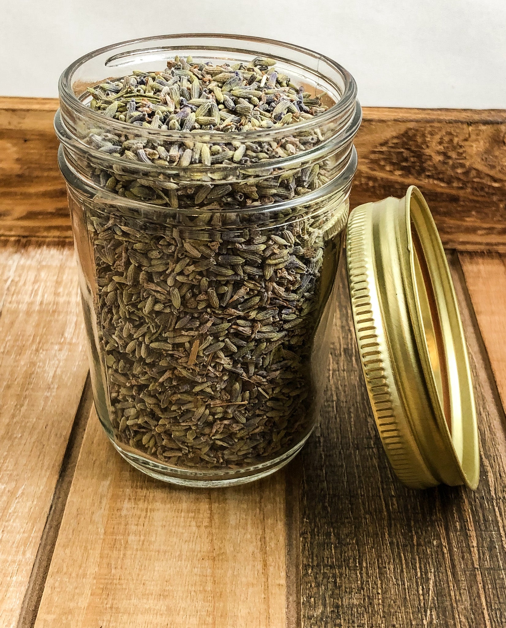 dried lavender in a clear mason jar with a wooden background