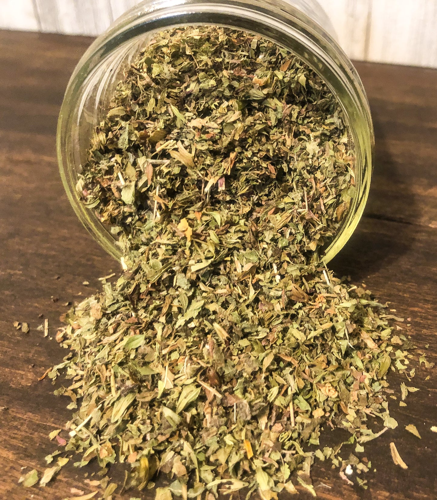 lemon balm spilling out of mason jar on wooden table 