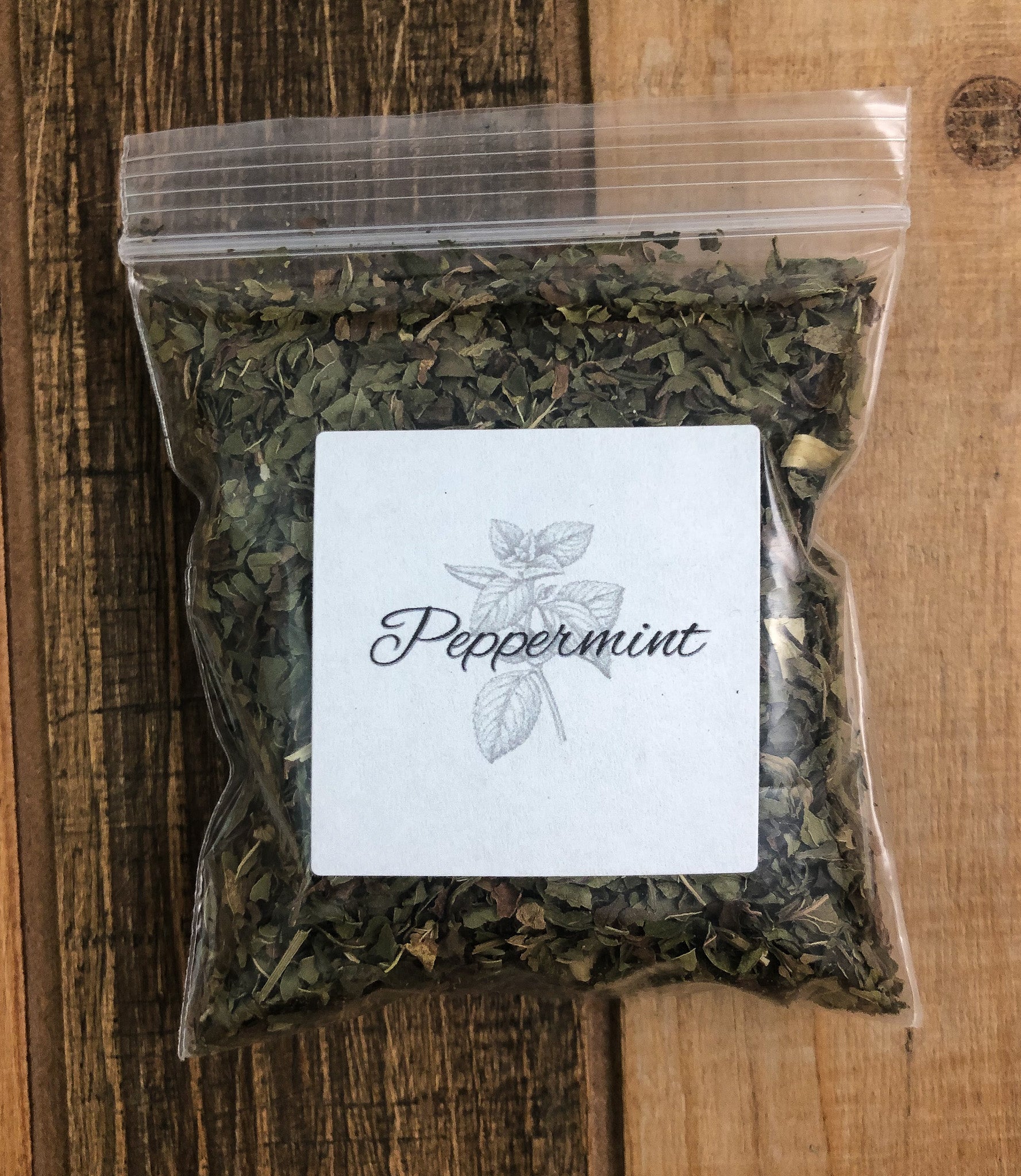 8g bag of dried peppermint in a clear plastic bag with a wooden background