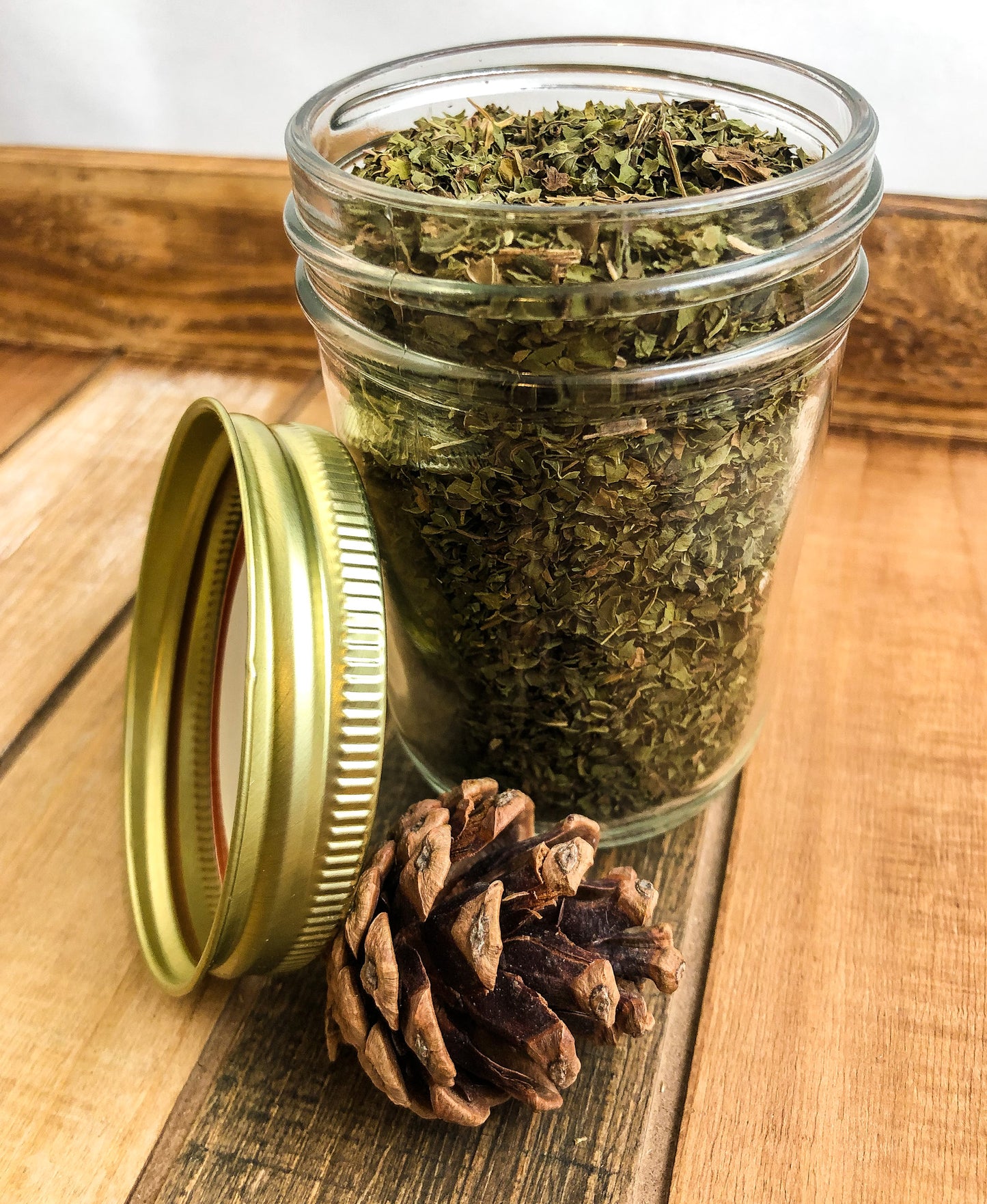 dried peppermint in a clear mason jar with a wooden background