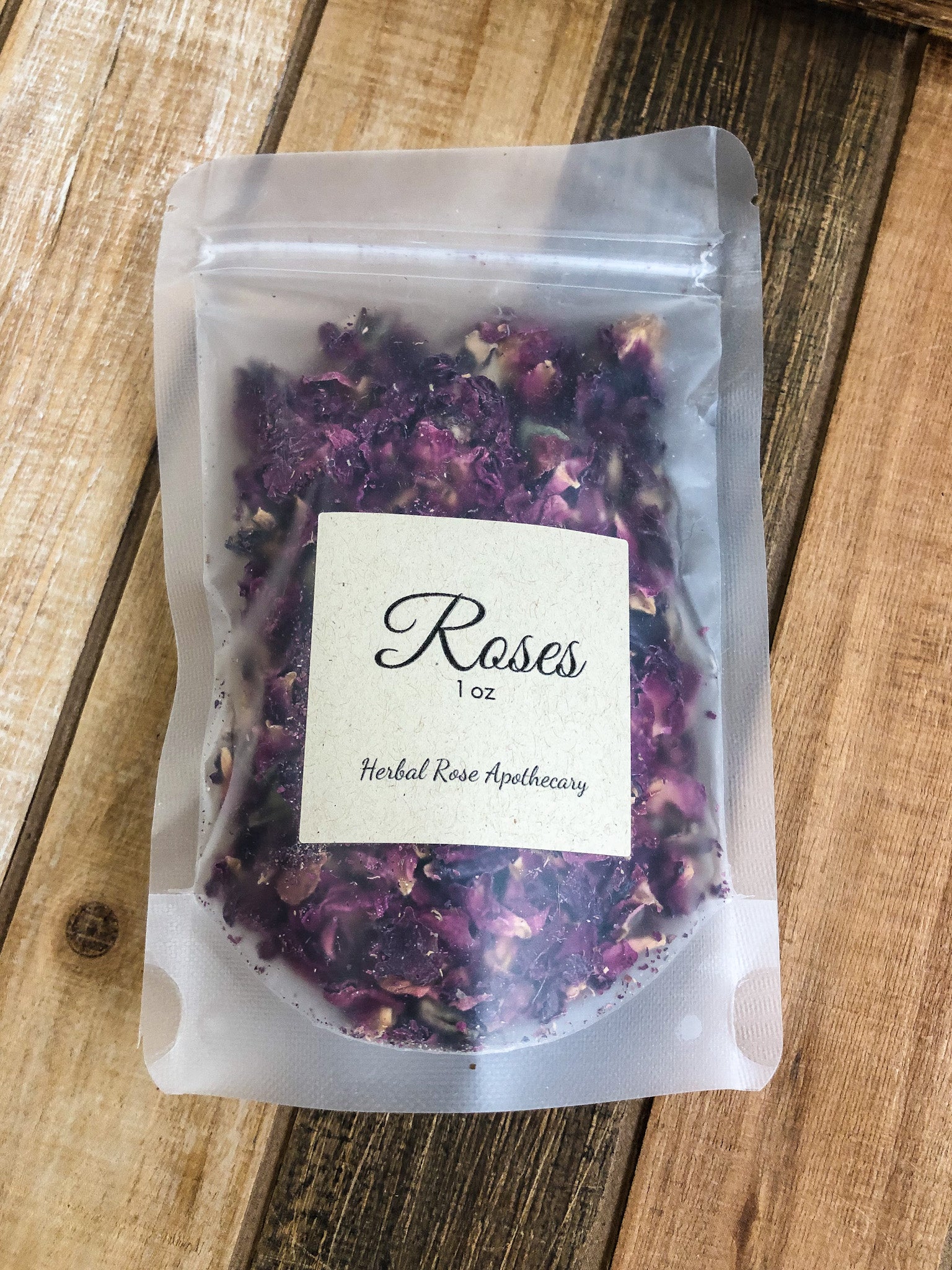1oz bag of dried roses in a clear plastic bag on a wooden background