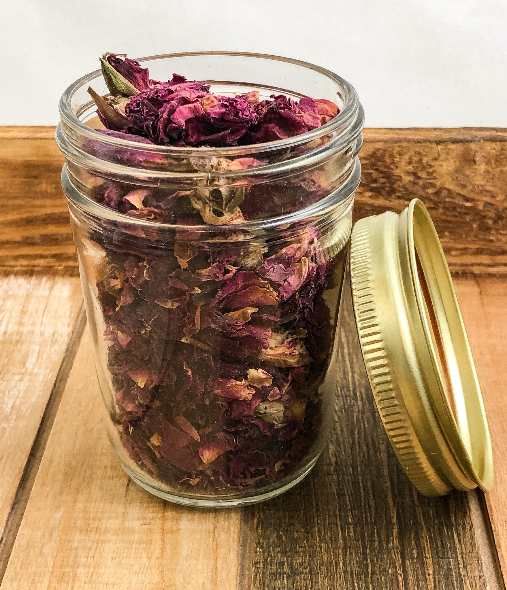 dried roses in a clear mason jar with a wooden background