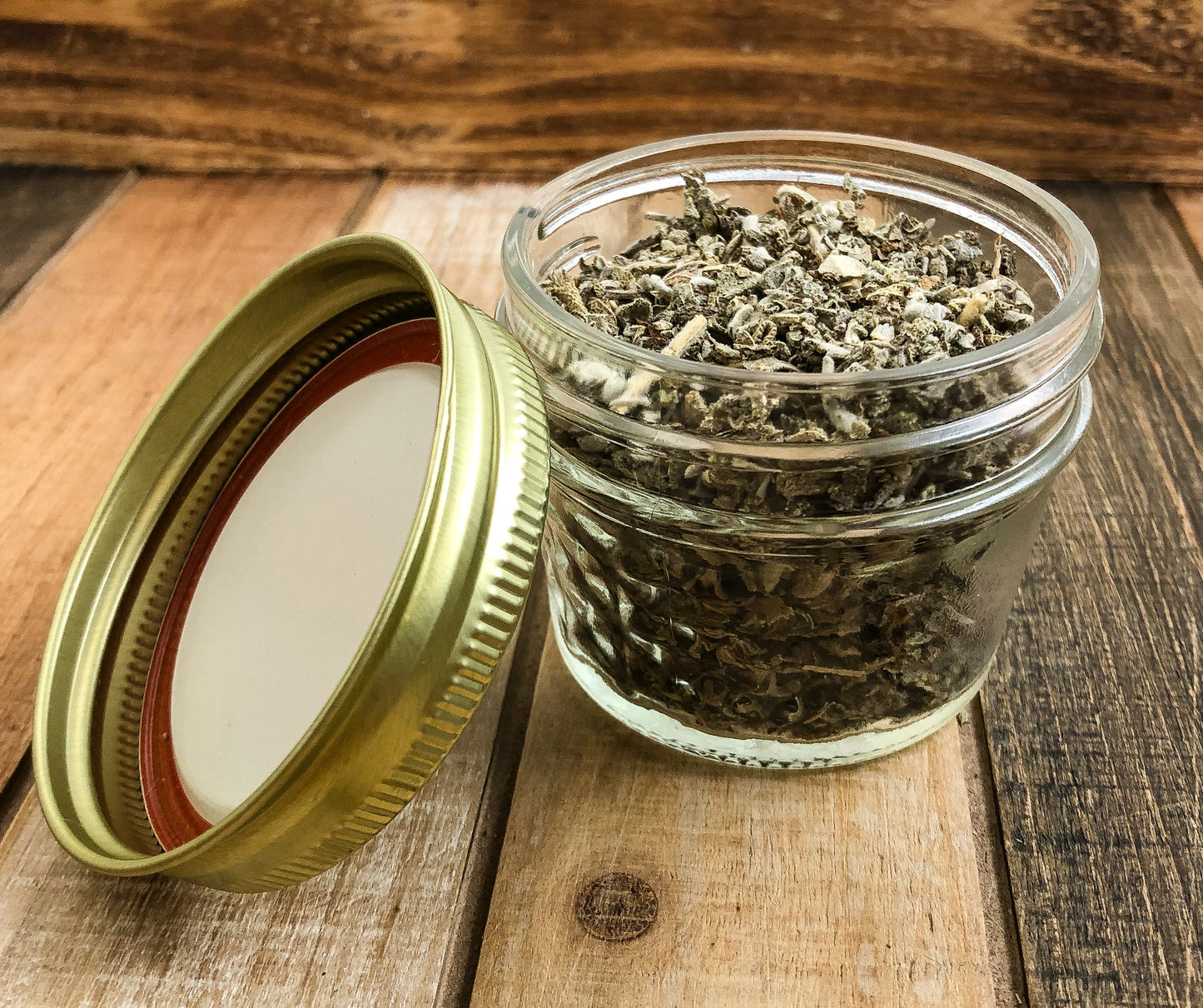 dried sage in a clear mini mason jar with a wooden background