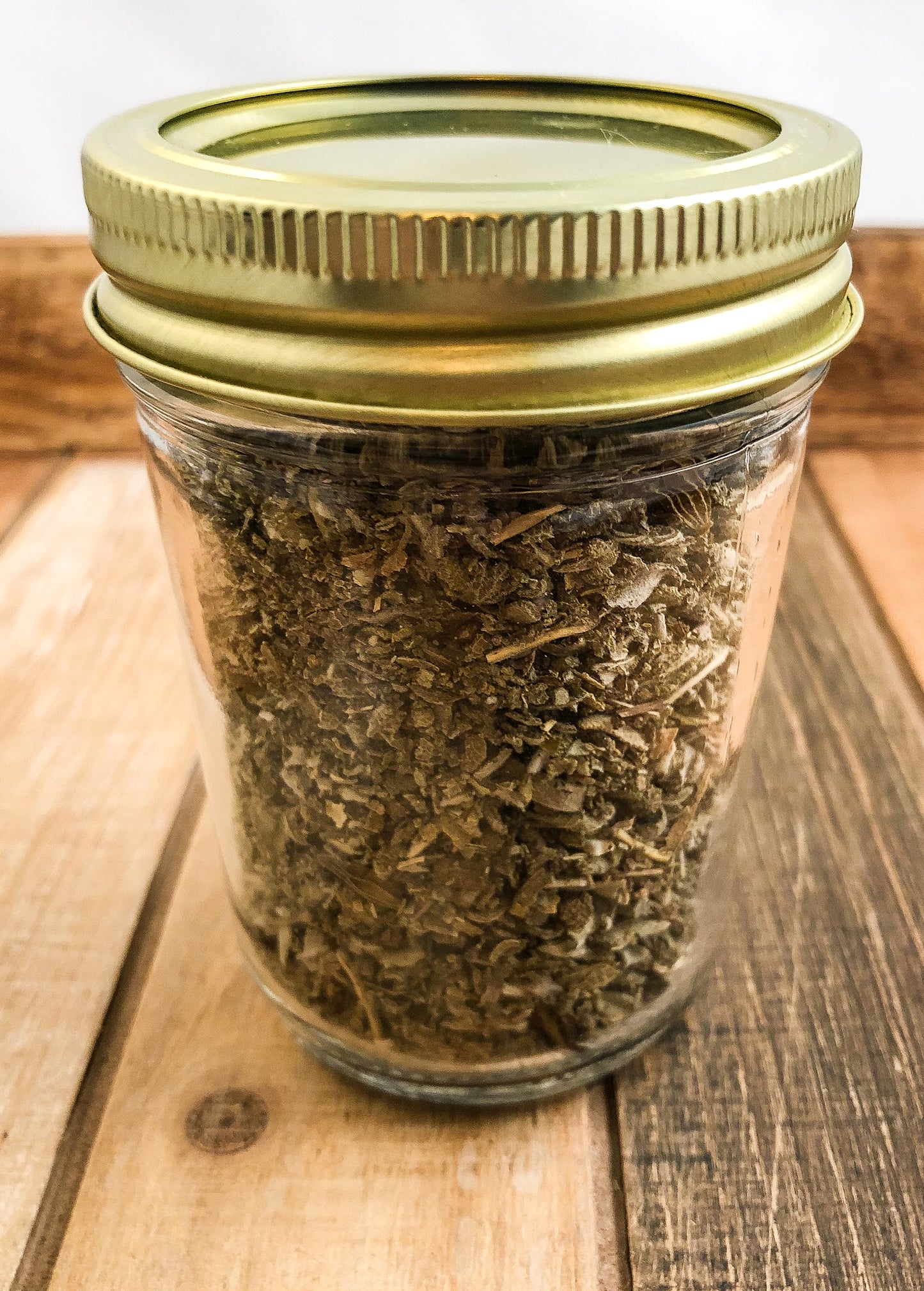 dried sage in a clear mason jar with a wooden background