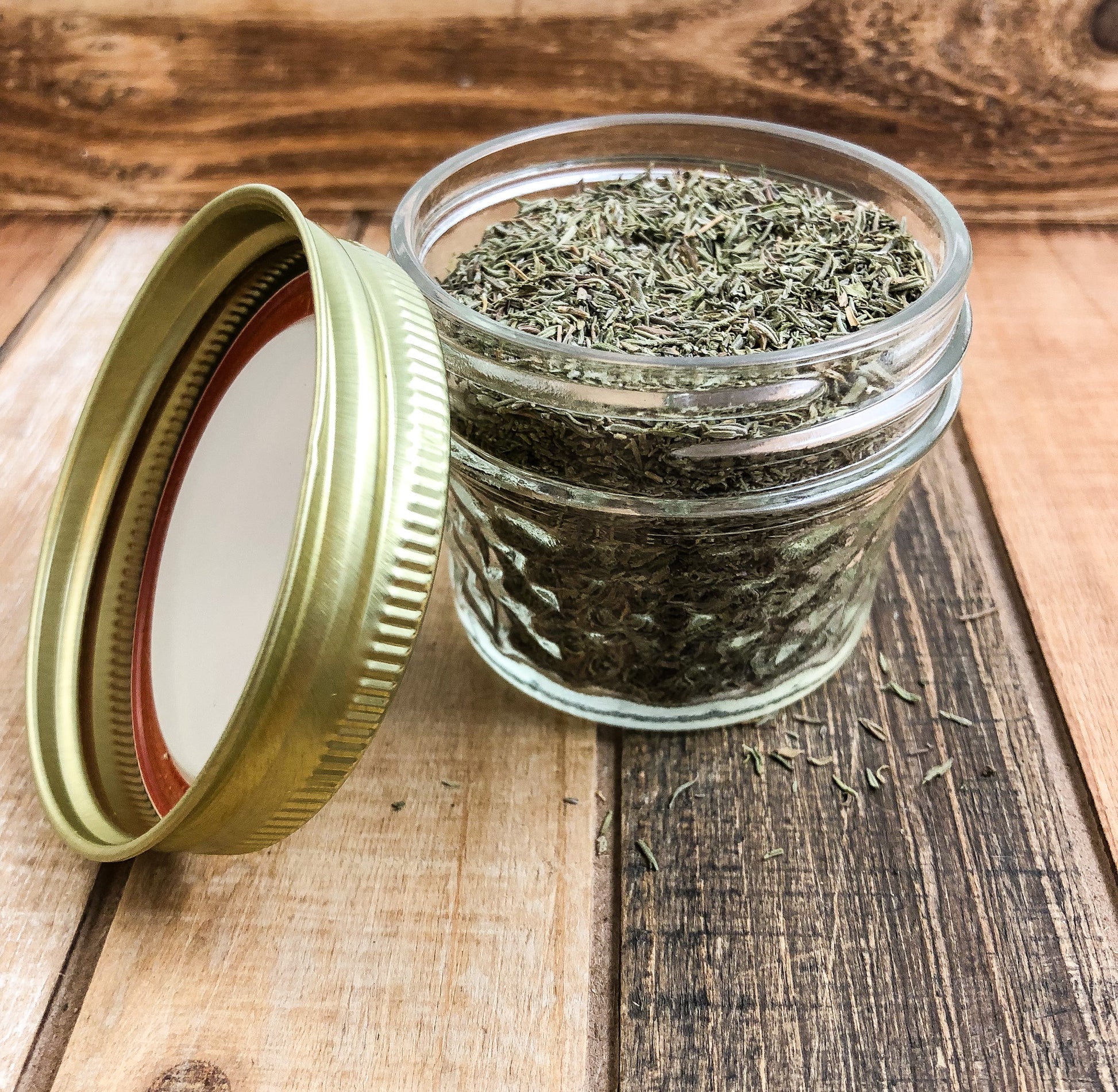 dried thyme in a clear mini mason jar with a wooden background