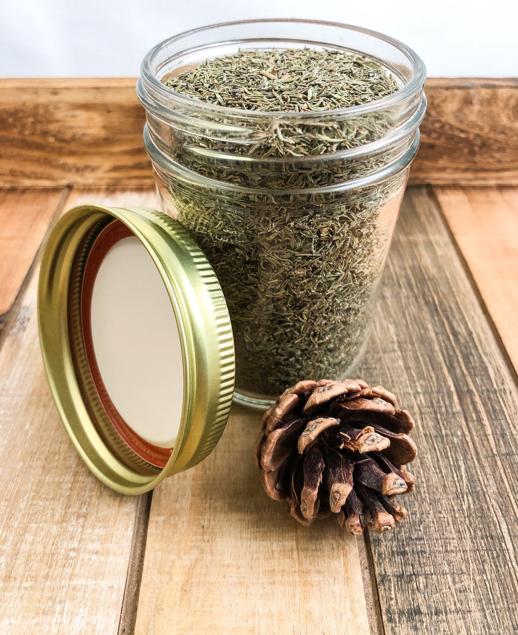 dried thyme in a clear mason jar with a wooden background