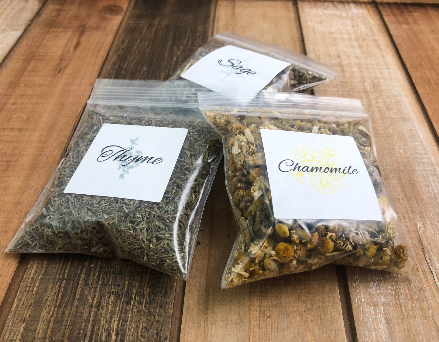 8g clear plastic bags of dried thyme, sage, and chamomile on a wooden background